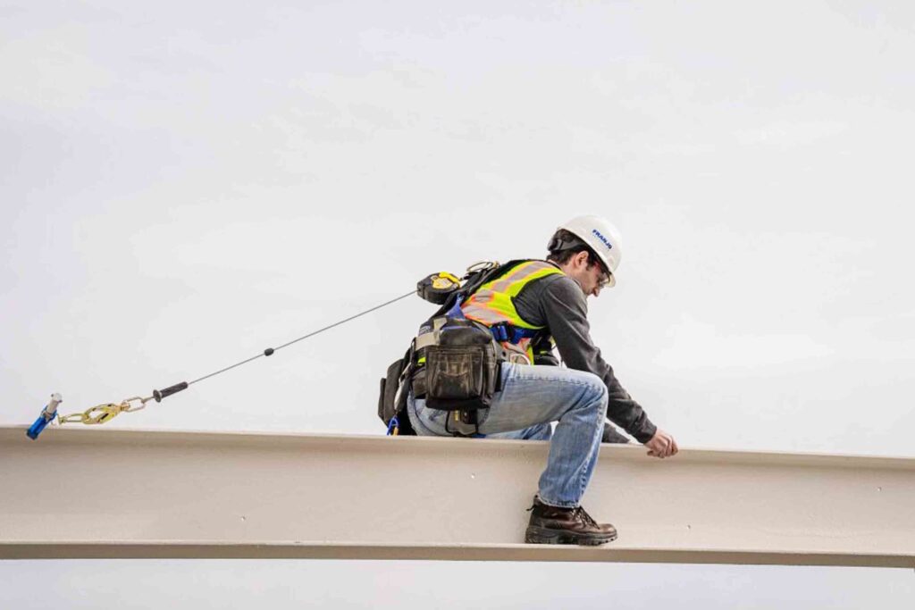Mann bei der Montage auf IPE Träger gesichert mit Zarges Absturzsicherung